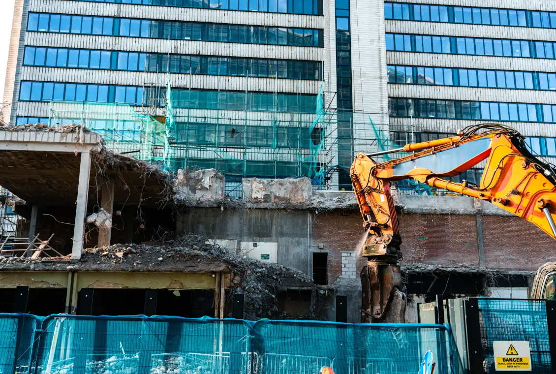 Building demolition with excavator in progress.