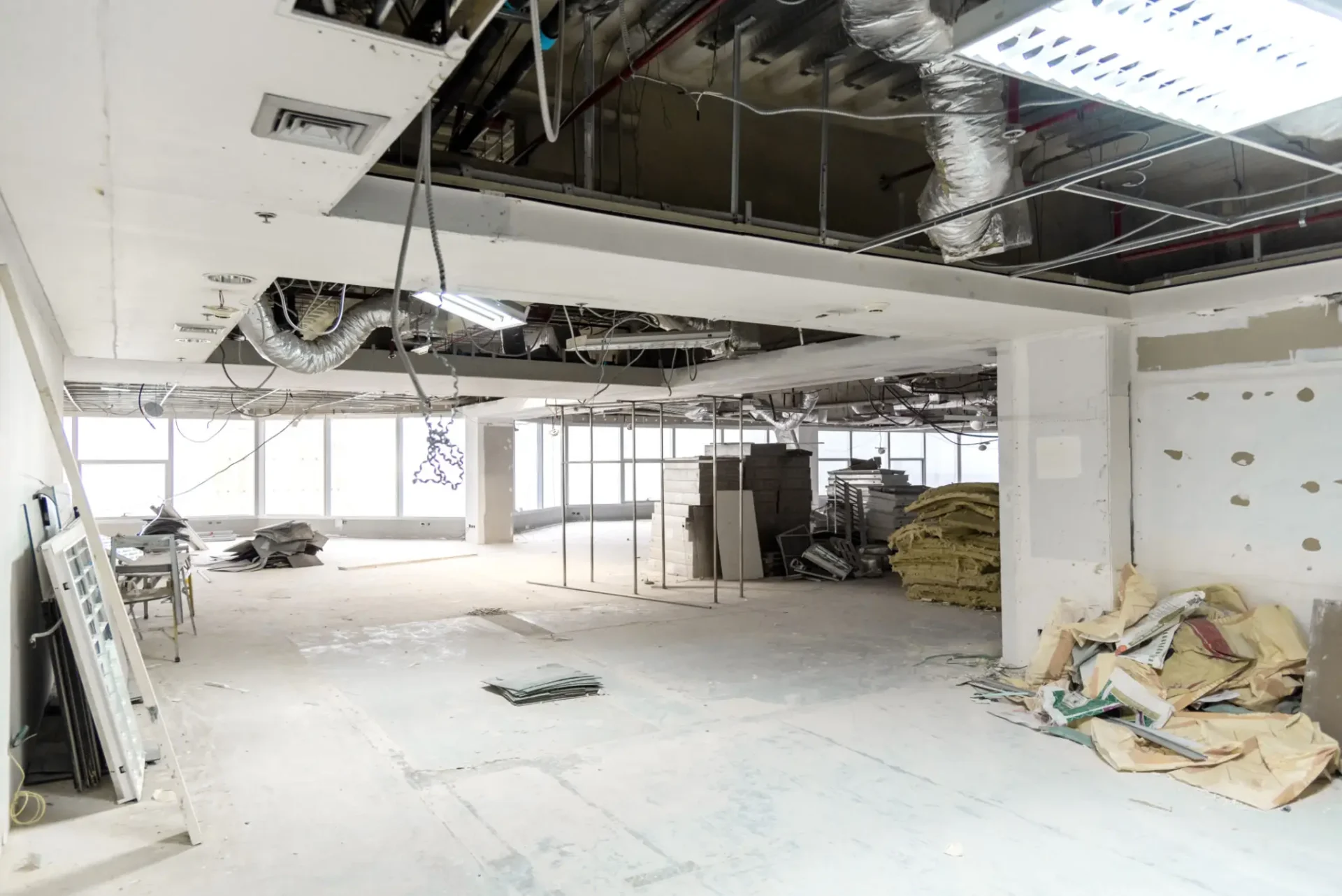 Interior of a building under renovation with exposed ceilings and construction materials.