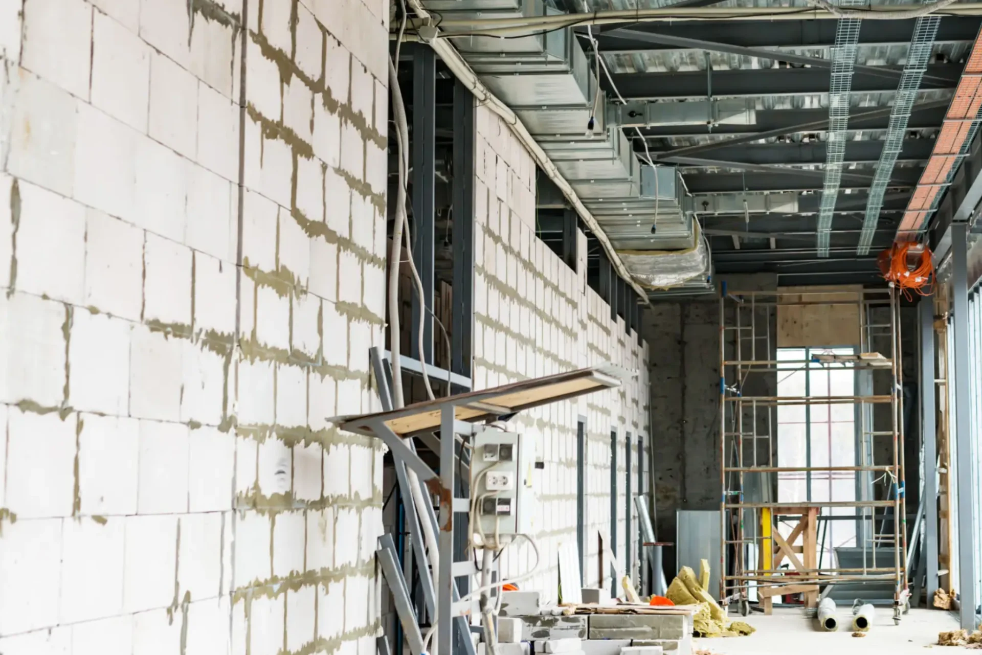 Interior view of a building under construction with exposed wiring and unfinished walls.